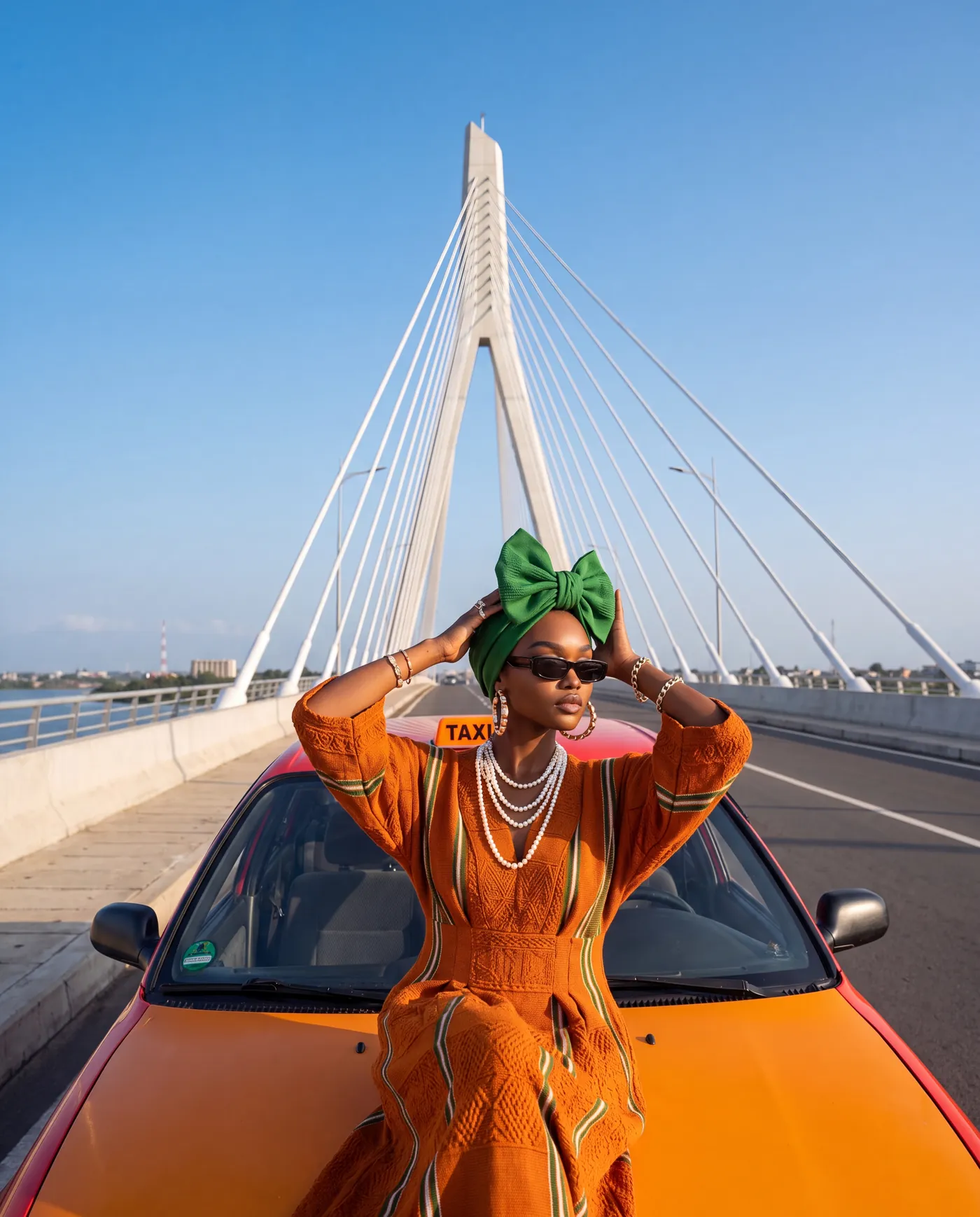 Femme en robe orange devant une voiture rouge, un pont de Dakar en arrière-plan