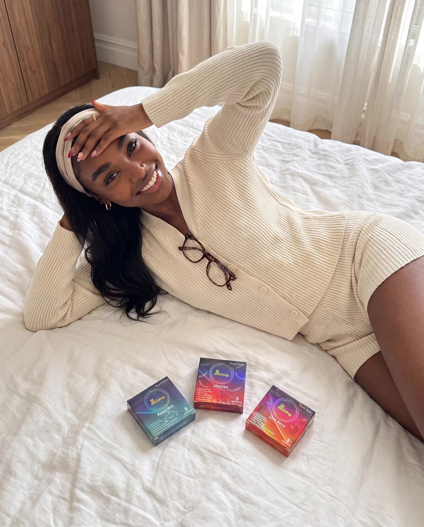 Femme allongée sur un lit, la main sur le front, des sachets colorés posés à côté d'elle