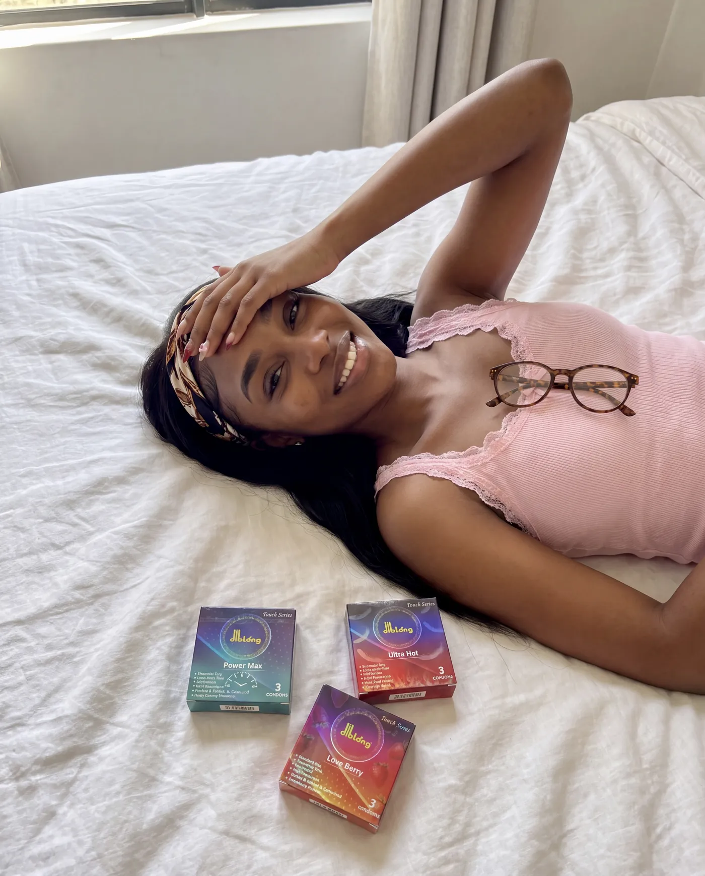 Femme allongée sur un lit, le bras replié, entourée de sachets de soin colorés